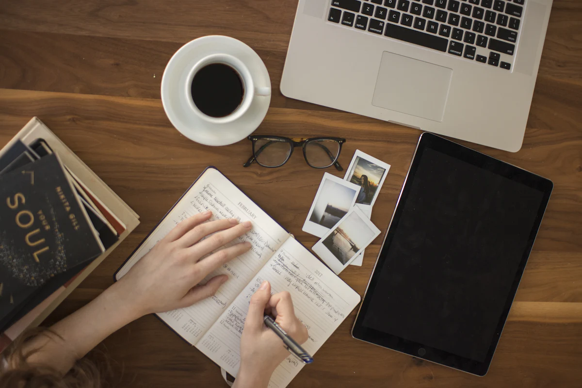 Writer drafting copy in a notebook next to a laptop